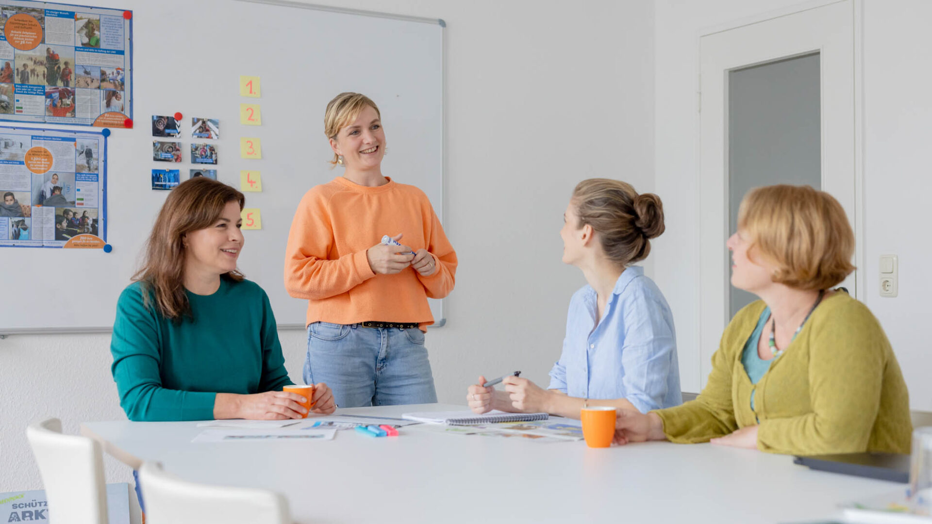 Vier Frauen stehen um einen Tisch und arbeiten gemeinsam.