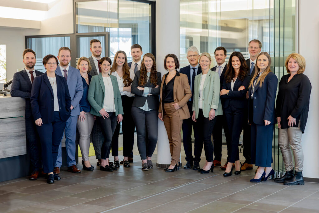 Teamfoto eines Unternehmens. Alle tragen Busines-casual. Sie lachen.
