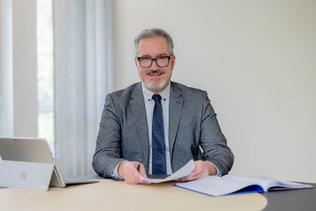 Seriöses Porträt eines Vermögensberater bei der Volksbank Oberberg. Er trägt einen Anzug und sitzt an einem Schreibtisch.