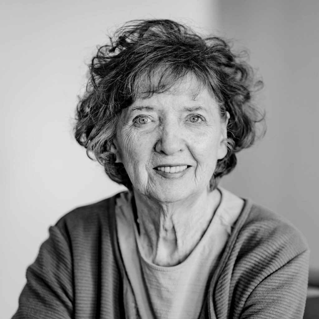 Schwarz-weiß Portrait eine Frau mit kurzen, lockigen Haaren. Sie lacht.