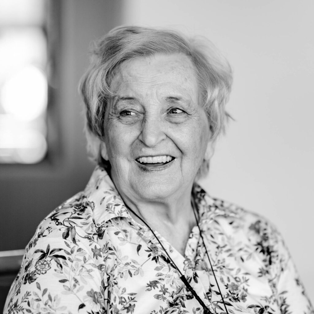 Schwarz-weiß Portrait einer älteren Frau mit kurzen Haaren. Sie lacht.