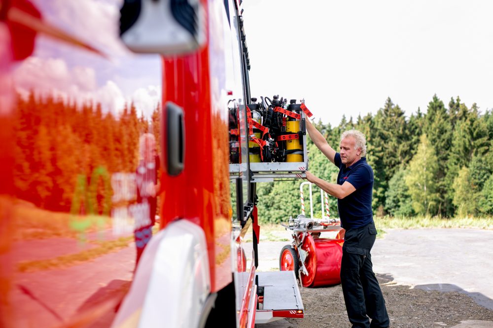 Ein Feuerwehrmann wie er das Equipment des Feuerwehrautos befüllt